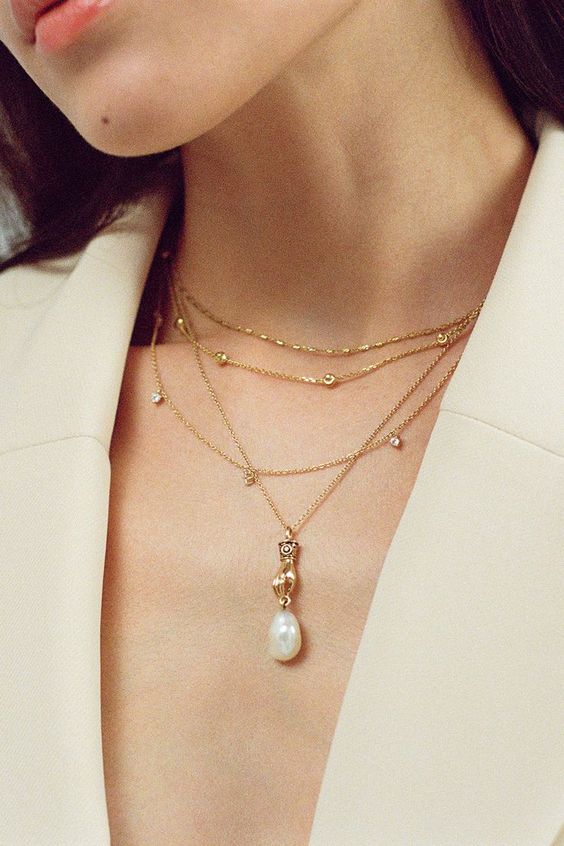 layered gold necklaces with rhinestones, beads and a large pearl will be perfect to accent a trendy modern bridal look