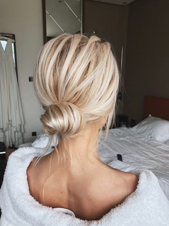 a classic low bun with a volume on top and some locks down is a cool idea for a modern bridesmaid look
