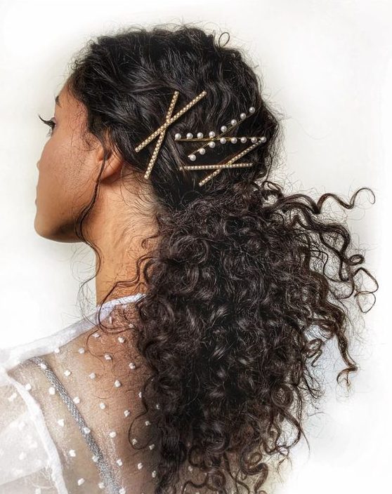 a curly low ponytail with a top accented with rhinestone and pearl bobbi pins is a simple and lovely idea