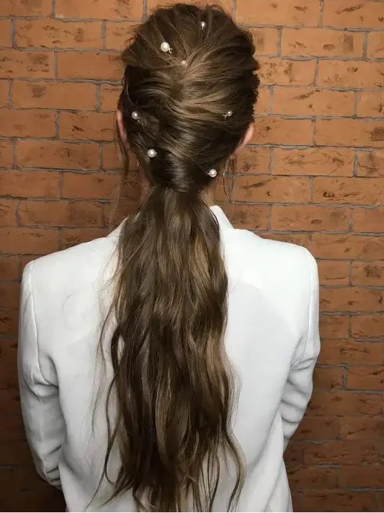 a wavy twisted low ponytail with some locks down and large pearl pins for a bolder accented look