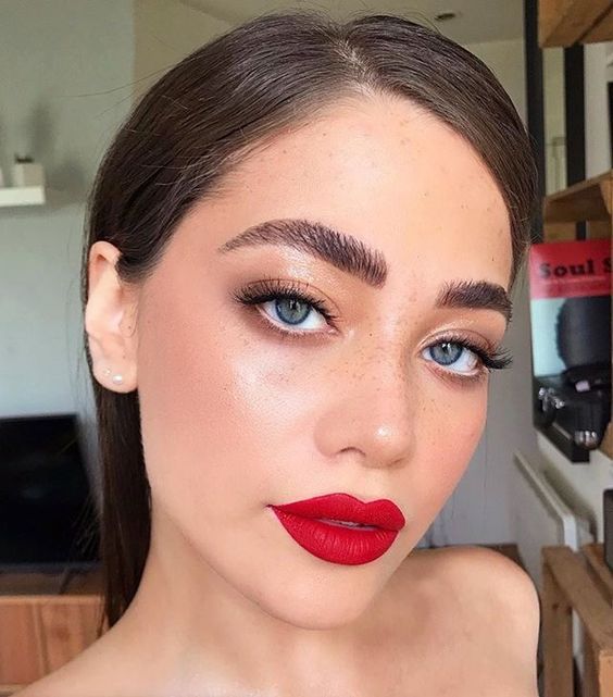 a catchy holiday makeup with a red lip, perfect tone with blush, fluffy eyebrows and shiny metallic eyeshadow