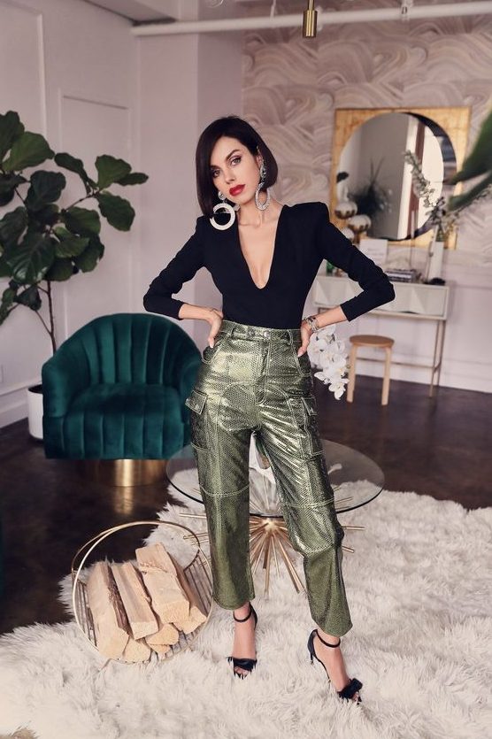 A jaw dropping look with a black top with a plunging neckline, metallic green pants, black shoes and statement earrings
