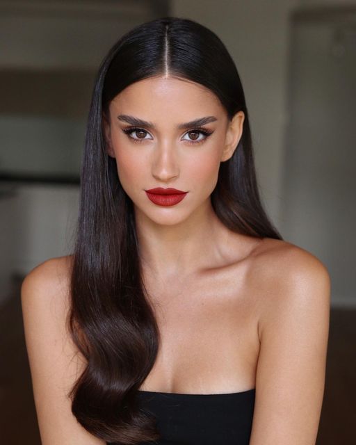 a refined holiday makeup with a red lip, perfect tone with blush, statement eyebrows and wings