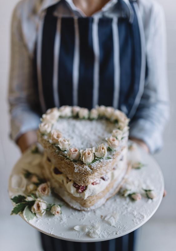 a naked heart-shaped wedding cake with fresh roses on top is a very cool idea for a garden wedding