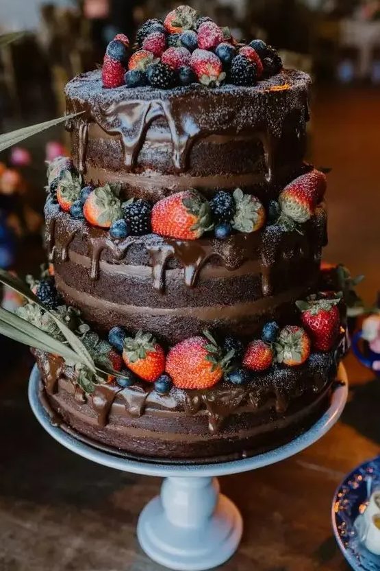 a naked chocolate wedding cake with chocolate drip, fresh berries and greenery is a gorgeous and delicious idea for any relaxed and laid-back wedding