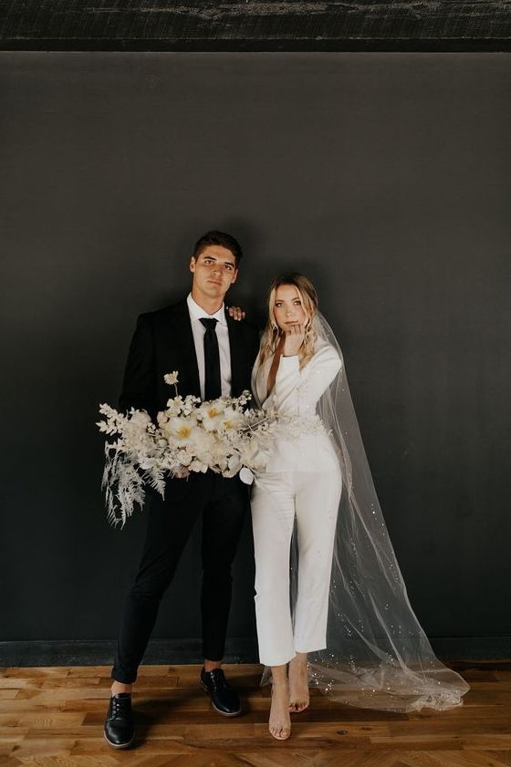 a white pantsuit with cropped pants and a blazer, tan shoes and a long embellished veil for a modern bride