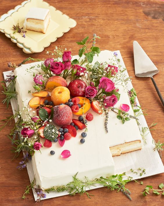 a buttercream sheet wedding cake topped with bright blooms, greenery and fresh fruit on top is wow