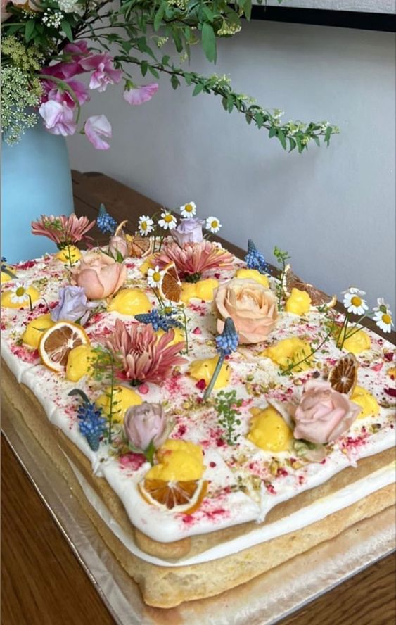a naked sheet wedding cake topped with fresh blooms in pastel colors and some citrus is amazing for summer