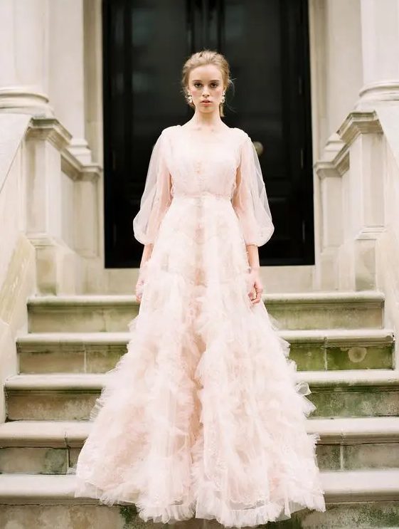 a light pink wedding dress with a V-neckline, puff tulle sleeves and a skirt with pink tulle appliques for a chic look