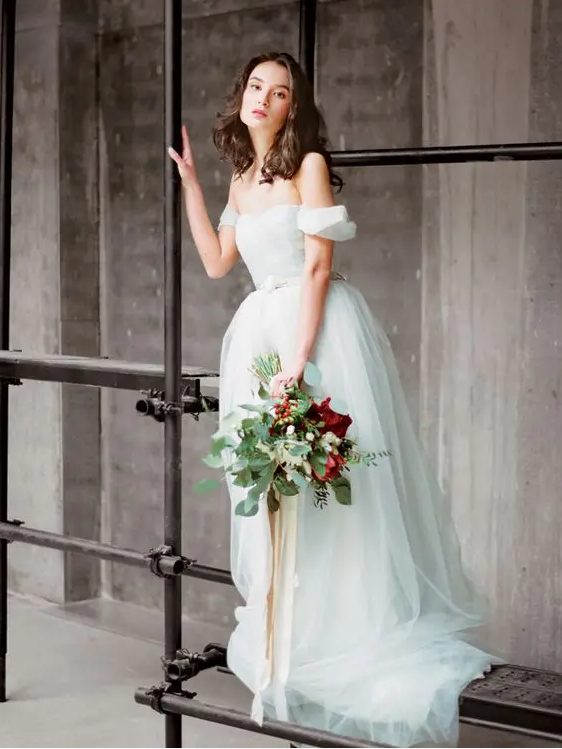 a light blue off the shoulder A-line wedding dress with an embellished belt and a full skirt
