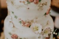34 a delicate and refined white wedding cake decorated with natural and sugar blooms, with sugar leaves and birdie toppers