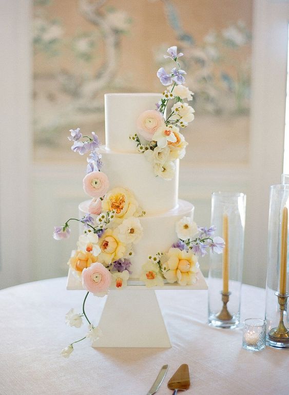 a white wedding cake with pastel blooms is a cool idea, fresh flowers instantly bring a fresh feel to the dessert table