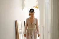 39 a neutral sheer wedding gown with embellishments all over it, a V-neckline, long sleeves and a bodysuit underneath