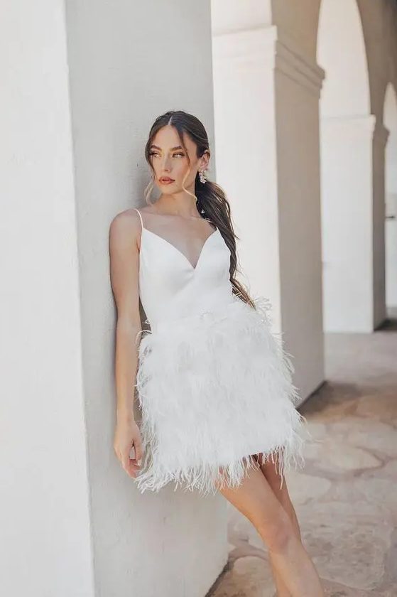 a mini wedding dress with a V-neckline and a feather skirt plus spaghetti straps is a lovely idea of a reception dress or playful mini dress