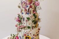 41 a fantastic wedding cake covered with white buttercream and with bright dried flowers and leaves pressed to it and attached for a voluminous look