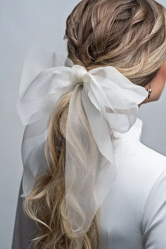 a twisted low ponytail accented with a large bow is a very glam and fresh idea for a modern bride