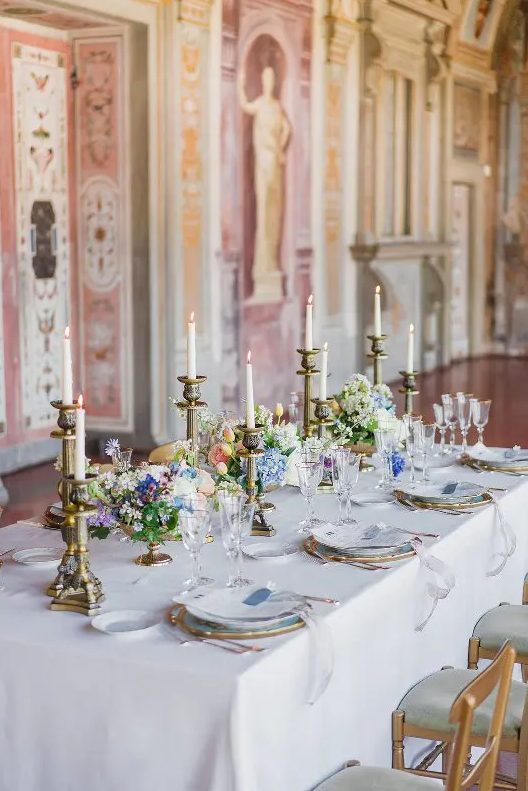 a sophisticated wedding tablescape with refined vintage candleholders, pastel blooms and greenery and white and blue porcelain
