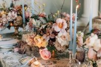 06 a fantastic wedding tablescape with a printed tablecloth, lush blush, peachy and mauve blooms, thin and tall blue candles and napkins