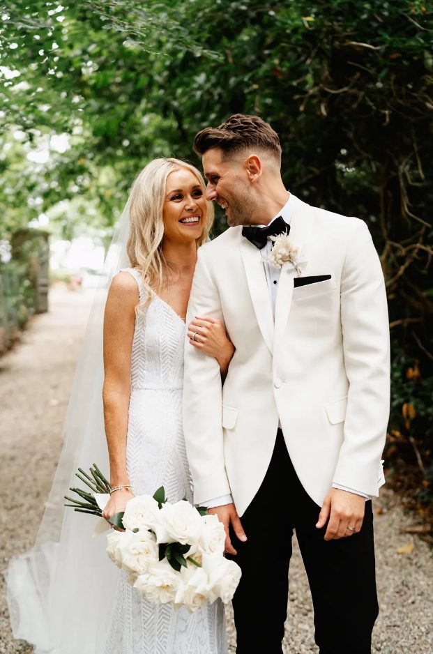 a gorgeous white tux with a white shirt, a black bow tie, dried flower boutonniere and black trousers