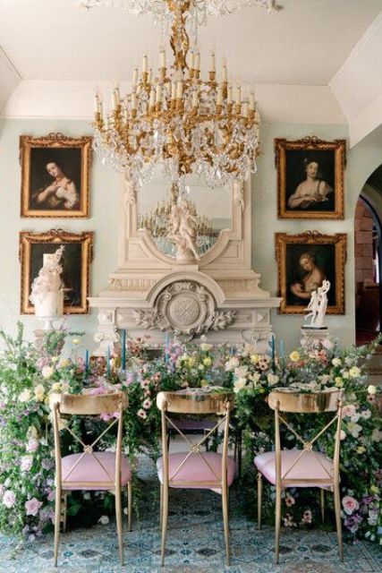a beautiful pastel wedding reception space with a table covered with lots of blooms and greenery and a gallery wall