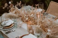 12 a chic desert boho tablescape with wooden plates, a fringe chandelier, candles, dried herbs and blooms plus pampas grass
