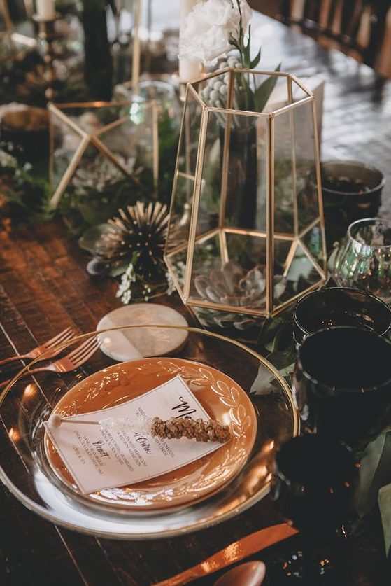 a boho tablescape with glass and porcelain plates, gilded terrariums with succulents and air plants, greenery and blooms