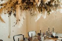 14 a boho chic tablescape with black napkins and candles, wicker chargers, geometric touches, dried florals and pampas grass