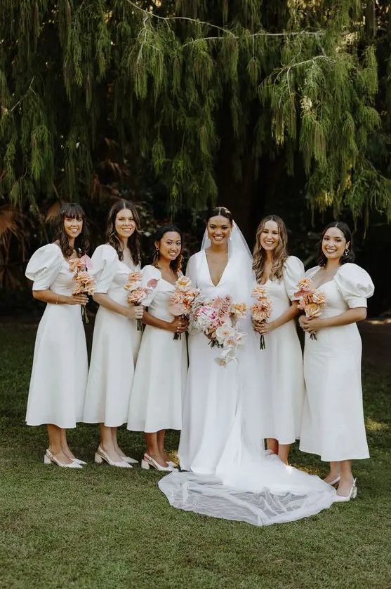 beautiful matching white midi bridesmaid dresses with deep necklines and puff sleeves plus white slingbacks are a very feminine idea