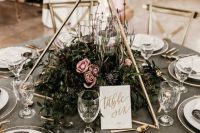 19 a 3D triangle with textural greenery and pink blooms and some floatign candles inside the centerpiece