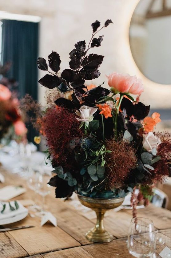 a boo lux wedding centerpiece of green and dark foliage, pink and blush blooms and smokebush