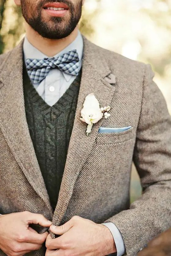 a light blue shirt, a cable knit waistcoat, a checked bow tie and a brown tweed jacket for a fall or winter groom