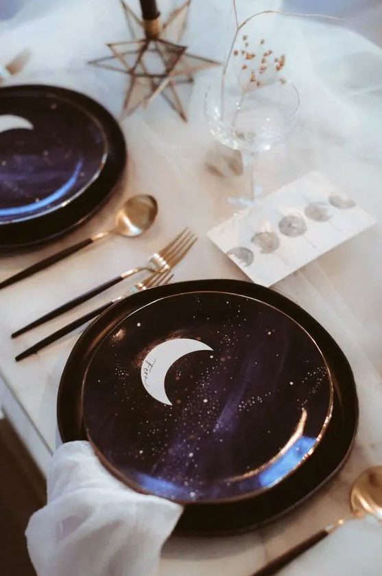 a celestial wedding tablescape with purple and gold porcelain, moons, stars and black and gold cutlery