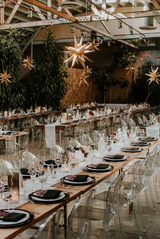 an elegant celestial wedding reception space with stars hanging down, clear chairs, black and white porcelain and black napkins