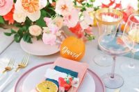 32 a bold and cheerful summer wedding tablescape with bright blooms, pink plates and napkins, gold rim glasses and cutlery