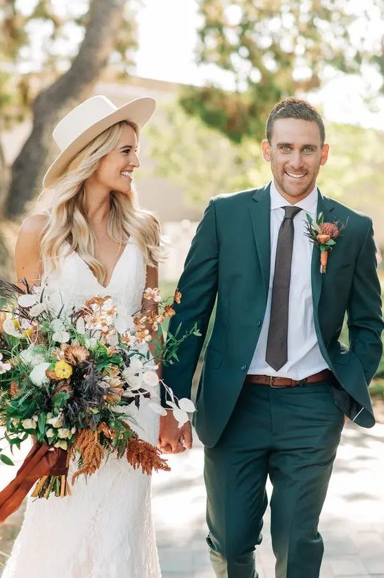 a classy green pantsuit, a white shirt, a black skinny tie, an amber belt and a bold floral boutonniere for a summer or fall wedding