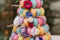 41 a colorful macaron tower decorated with bold blooms and leaves is a fantastic alternative to a wedding cake