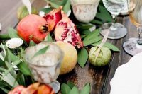 43 a fall wedding table runner of greenery, apples, pomegranates and candles is a very lush and cool idea