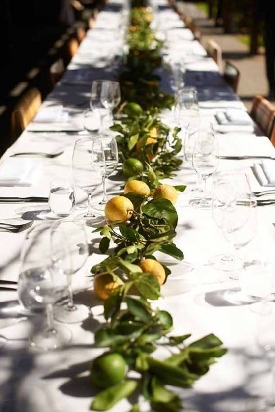 a bright citrus wedding table runner of lemons and limes and greenery is a very cool and summer-like idea