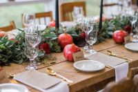 46 an exquisite fall wedding table setting with a greenery and burgundy bloom runner, pomegranates and black candles, gold cutlery