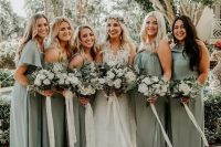 49 mismatching sage green bridesmaid dresses and a white lace wedding dress with a layered skirt