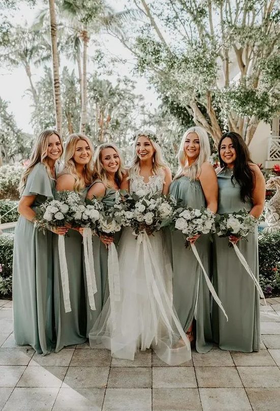 mismatching sage green bridesmaid dresses and a white lace wedding dress with a layered skirt