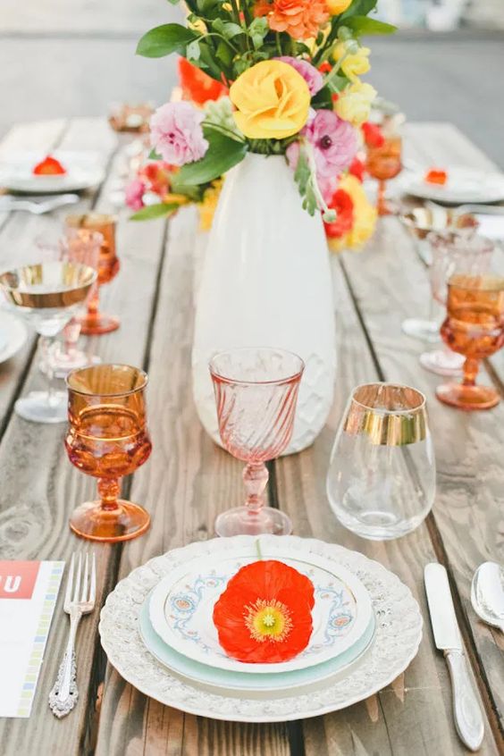 a summer wedding tablescape with patterned plates, bright blooms, amber and blush glassware