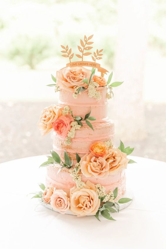 a Peach Fuzz wedding cake decorated with ornage and peachy roses, greenery and a sign topper is a lovely idea