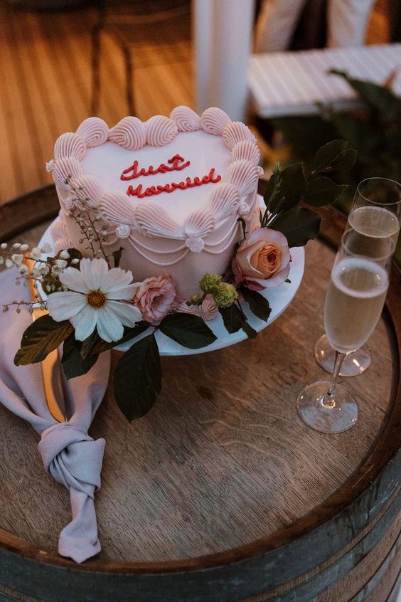 a blush heart-shaped wedding cake with red calligraphy and sugar detailing is a lovely vintage-inspired idea