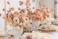 a chic wedding tablescape with multiple peachy and neutral blooms, woven placemats, a blush table runner and gold cutlery