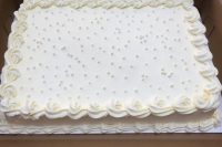 a classic white sheet wedding cake topped with icing and pearls on top is a refined and edgy dessert for a wedding