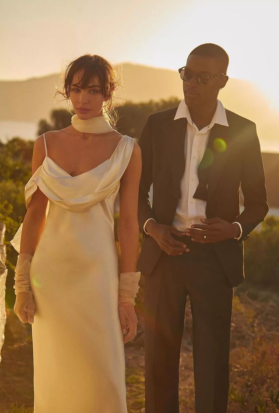 a creative wedding dress with a unique neckline and a spaghetti strap, sheer gloves and a scarf for a unique and catchy look