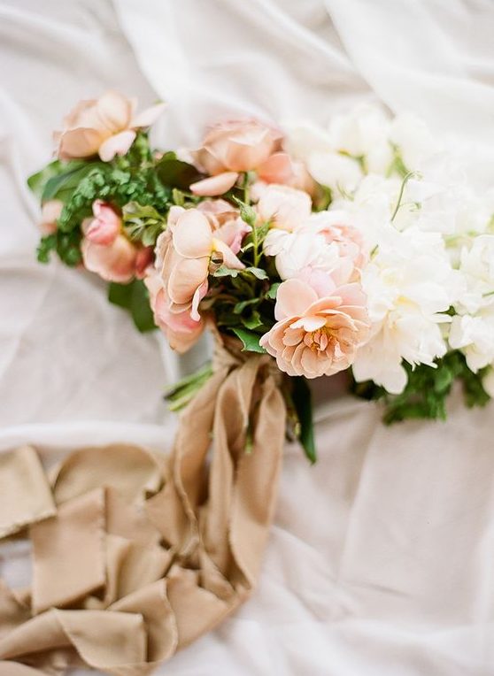 a delicate wedding bouquet with peachy and white blooms and greenery and tan colored ribbons is a beautiful idea