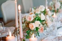 a dreamy wedding tablescape with a blush runner, peachy candles and napkins, greenery and white porcelain is chic