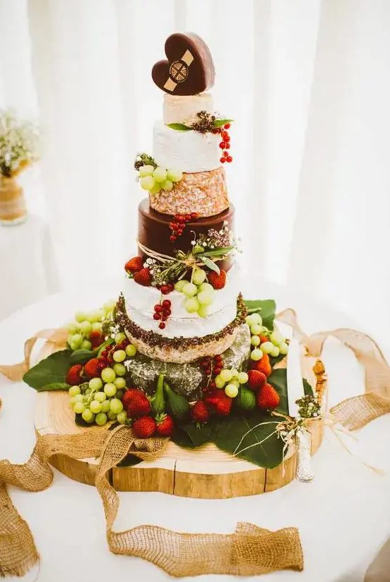 a fantastic cheese wheel wedding cake with fresh grapes, strawberries placed on a palm leaf is an amazing idea for a summer wedding